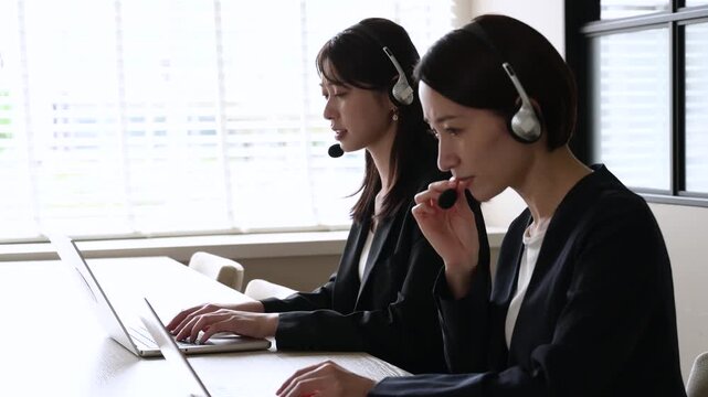 パソコン越しに謝罪をするスーツの日本人女性