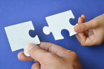 Connecting puzzle pieces in hands, hand holding puzzle.