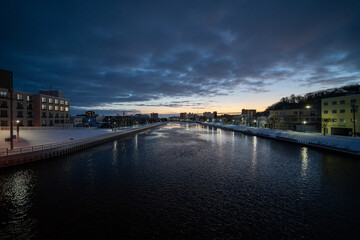 Fototapeta premium Winter dawn over Abashiri city river in Hokkaido, calm urban landscape with reflections, cold morning sky and copy space background