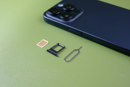Smartphone with SIM card tray, SIM cards, and ejector tool isolated on a green background. Concept of mobile connectivity, telecommunication, network access, perfect for technology, telecom