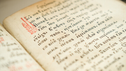 Fototapeta premium Old Bible book. Close-up of ancient religious text written in ancient Slavic letters, Cyrillic.