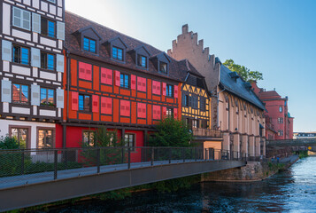 Naklejka premium Strasbourg, France. Bright half-timbered houses of the Petite France district on the embankment of the Ille River with footbridge in the foreground in the early morning.