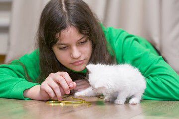 A European girl plays with a white kitten