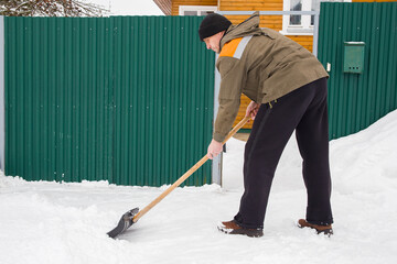 A European man shoveling snow near his home.