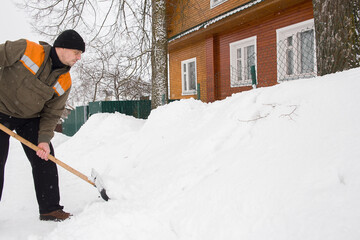 A European man shoveling snow near his home.