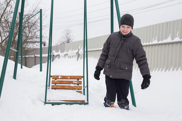 A European boy walks through deep snow.