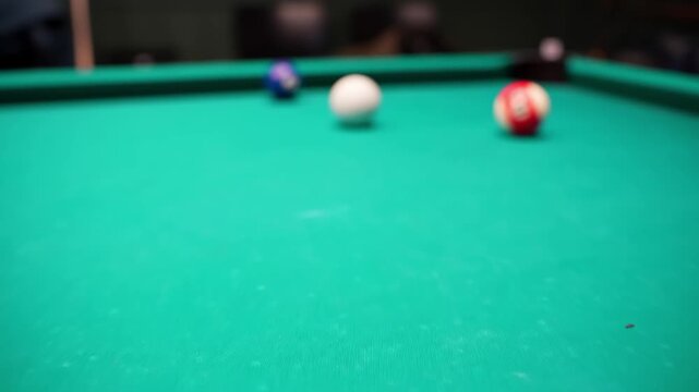 Shallow focus shot of yellow 1 and black 8 on green baize billiards table, cue ball nearby in a cozy game room with cinematic bokeh.