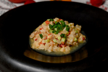 Vegetable tartare with green onions in a black deep plate