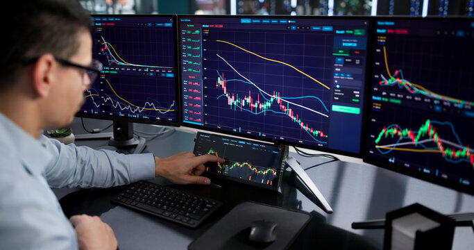Busy Hispanic Stock Broker Using Multiple Monitors
