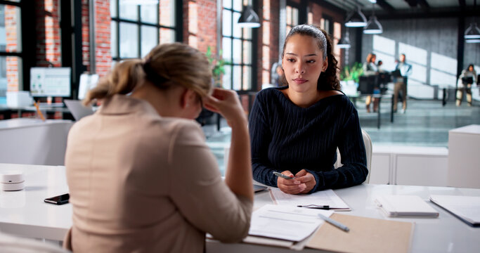 Young Woman Attends Employment Interview In Busy Office