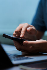 Close-up of hand holding a smartphone, finger touching the screen. Concept for using social media,...