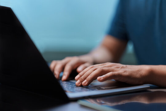 Close-up of hands typing on a laptop keyboard. Concept for business, remote work, programming, or freelance lifestyle. Man working with modern technology in an office or home environment. Searching.