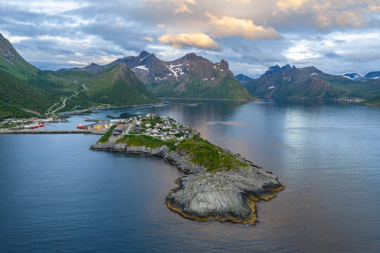 12 july 2025, Hus&oslash;y, Norway. Aerial, drone view of little villate Husoy and island in &Oslash;yfjorden fjord during sunset. Beautiful nature, mountains surrounding fjord, wonderful golden reflection from the