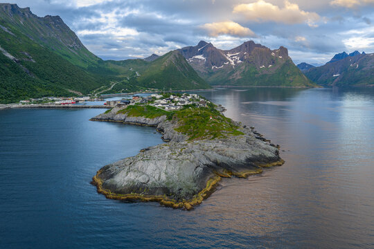 12 july 2025, Hus&oslash;y, Norway. Aerial, drone view of little villate Husoy and island in &Oslash;yfjorden fjord during sunset. Beautiful nature, mountains surrounding fjord, wonderful golden reflection from the