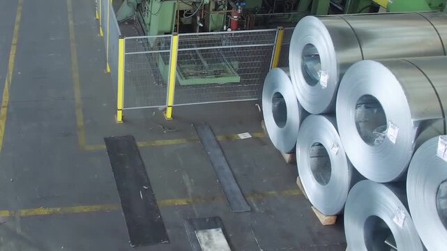 Top-down aerial perspective of warehouse with neatly arranged metal coils representing heavy industry concept