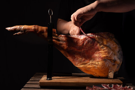Leg of Iberian ham being cut by an expert.
