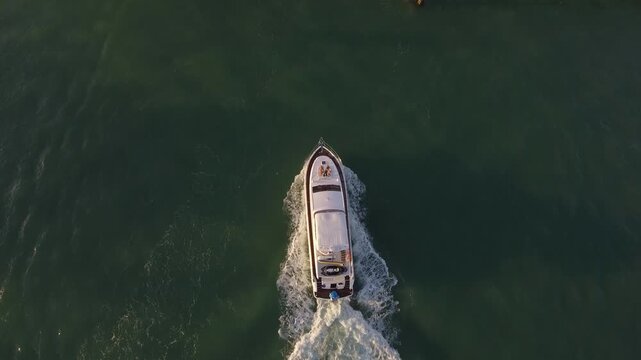 Overhead drone view shows a boat moving through calm water with a clear wake.