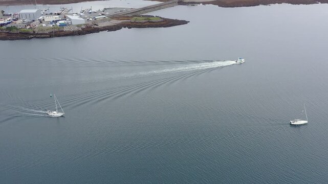 Drone shot of three yachts sailing out of Stornoway harbour into the Minch.