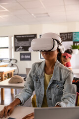 Diverse students with vr headset sitting on desk in classroom