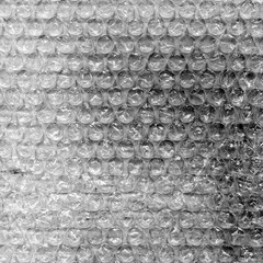 High contrast bubble wrap texture on black background with glowing light reflections. Abstract plastic pattern, futuristic industrial surface, dramatic lighting, creative packaging concept.