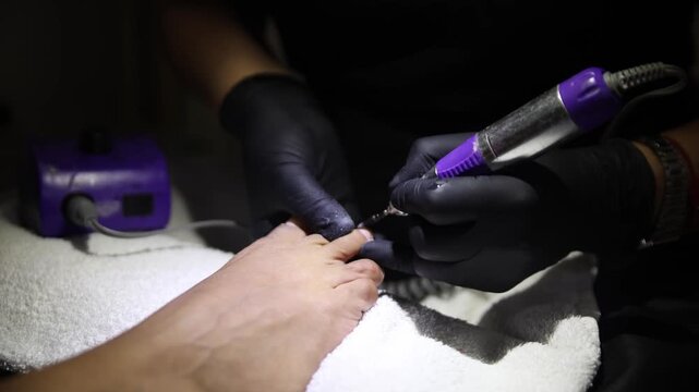 Gloved Hands Using Electric File for Pedicure on Latina Woman's Feet