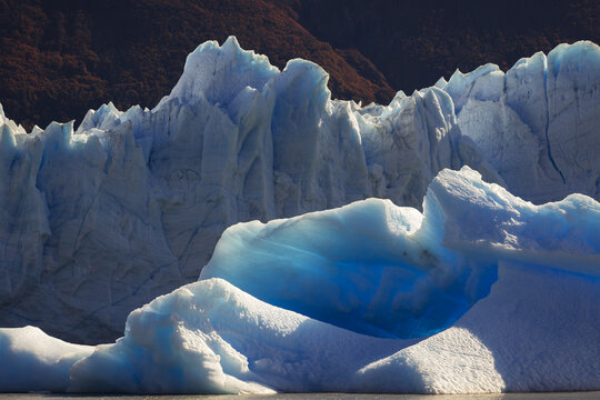 View of a colossal glacier, its icy surface shimmering with ethereal blue hues against a backdrop of rugged terrain, Santa Cruz, Santa Cruz Province, Argentina.