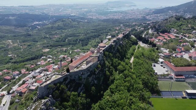 Aerial views of the entire Klis Fortress on a rocky cliff with a slight rotation Croatia