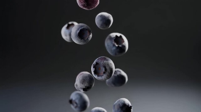 A close-up view of several dark blue, juicy fruits suspended in mid-air against a gradient background transitioning from black to light grey