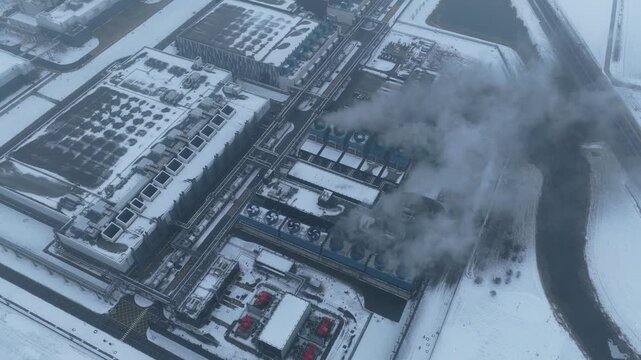 Aerial view of data center with cooling towers emitting steam in winter