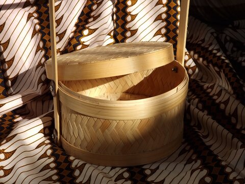 Round woven bamboo container with open lid on parang batik