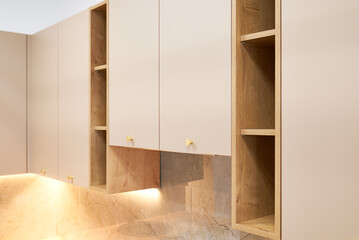 Fototapeta premium Contemporary kitchen cabinets with lighting, open shelving and gold handles.