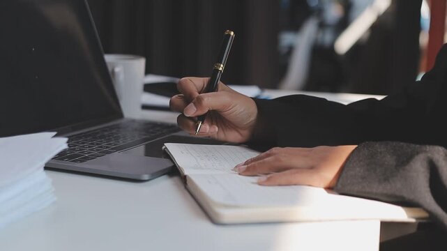 Elearning. Close up of smiling young female remote student watch training lecture on laptop pc take notes at paper workbook by hand. Millennial lady get distant education write thesis of online lesson