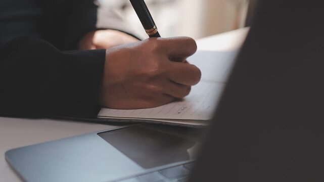 Elearning. Close up of smiling young female remote student watch training lecture on laptop pc take notes at paper workbook by hand. Millennial lady get distant education write thesis of online lesson