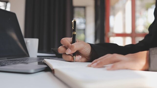 Elearning. Close up of smiling young female remote student watch training lecture on laptop pc take notes at paper workbook by hand. Millennial lady get distant education write thesis of online lesson