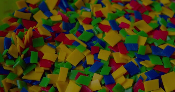 Footage of small vivid plastic pieces prepared for recycling purposes.