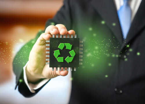 A businessman holds a computer microchip with a recycling symbol in his hand. Recycling of electronic waste. Extraction of valuable metals. Preventing harmful impact of electronic waste on environment