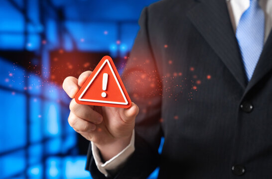 A businessman warns of something unacceptable by holding a sign of attention. Red flags for a business leader. A serious breakdown, accident, or error. Crisis alert, risk prevention