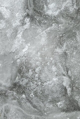 Obraz premium Dense natural ice texture with frozen air bubbles and cracked icy surface. Cold abstract winter background suitable for design, beverages, cosmetics, overlays, and copy space.