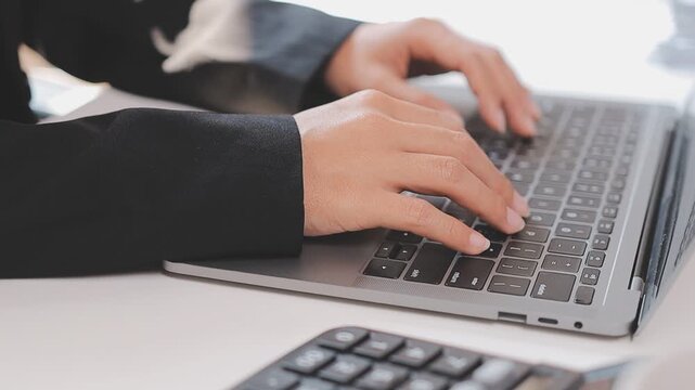 Closeup of the hands of a receptionist typing and sending emails while working in an office alone. One secretary doing admin and writing reports while organizing a schedule for her manager at work