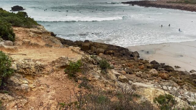 Rocky path through dry scrubland terrain with pine Rocky footpath cutting through dry coastal scrub and pine trees near Zavial Beach, with muted light and cloudy skies shaping a raw Atlantic landsca