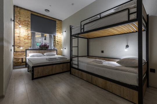Modern loft hostel room with double bed and wooden bunk beds at night