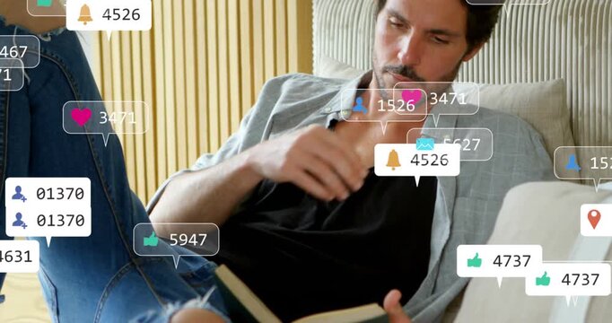 Animation of social media icons floating over man reading a book on the bed at home