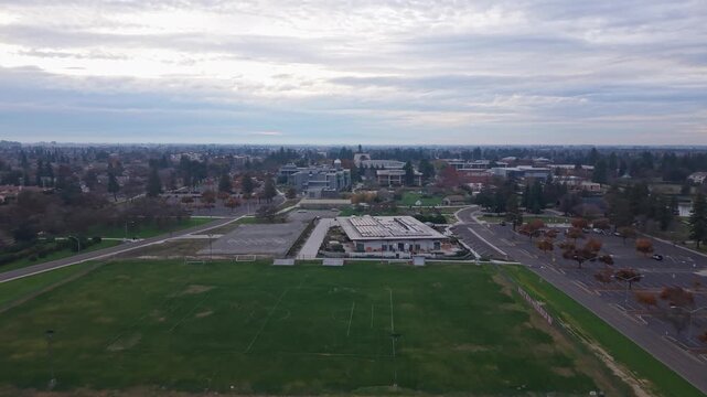 A drone zoom out captures CSU Stanislaus as clouds drift overhead, revealing campus buildings, tree-lined walkways, and the calm Turlock landscape.
