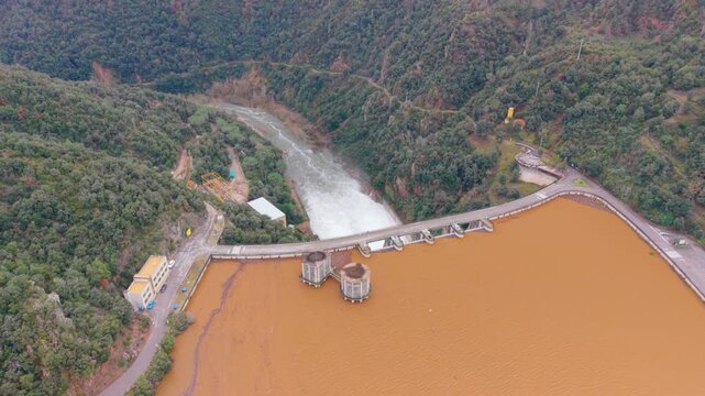Sau pantano overflowing, january 2026 high angle view of a dam releasing large volumes of brown, muddy water. Climate change and heavy rains causing flash floods in a reservoir
