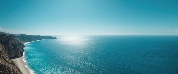 Obraz premium A stunning scene of the blue ocean along the rugged coastline, set against a wide sky and untouched beach, illustrating nature's landscape charm