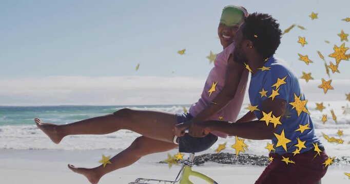 Couple posing on yellow bike at beach, sharing glance and initiating star confetti for marketing
