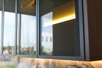 Fototapeta premium Modern kitchen cabinets with glass fronts, aluminum frames and lighting.