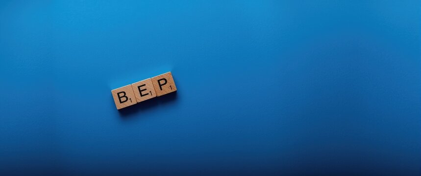 Business Concept: Wooden letter cubes spelling BEP on blue background with ample copy space