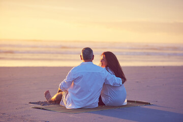 Fototapeta premium Hug, relax or sunset with couple on beach together for anniversary, bonding or relationship. Back, ocean space or scenic view with mature people embracing on sand at coast for love, security or trust