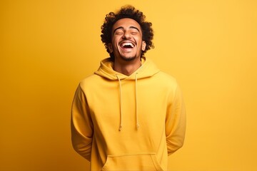Fototapeta premium Happy young man with curly hair laughing heartily on yellow background